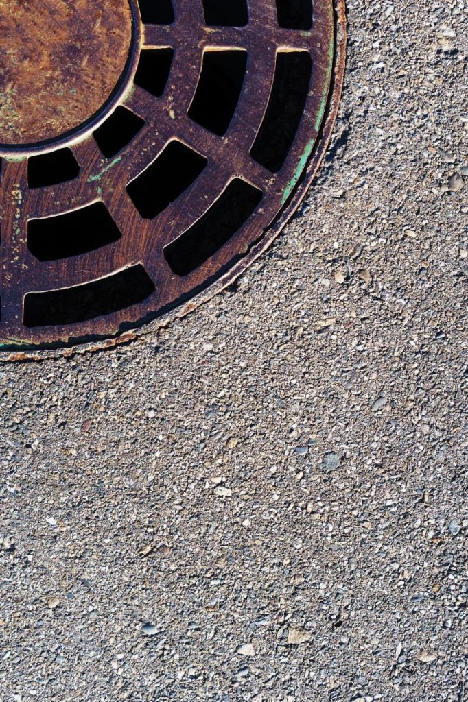 Sewer round hatch with a grate on an asphalt road.